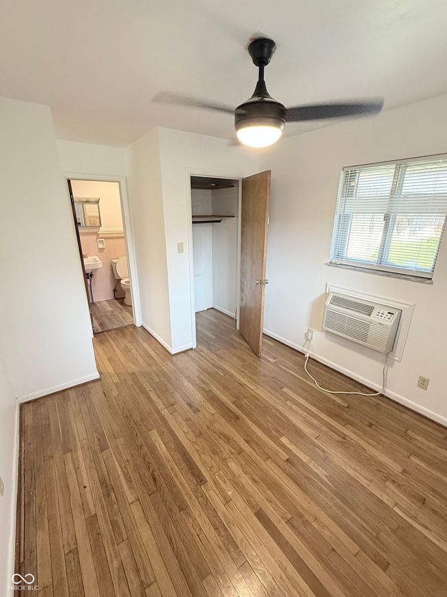 unfurnished bedroom with hardwood / wood-style flooring, an AC wall unit, a closet, and ceiling fan | Image 9