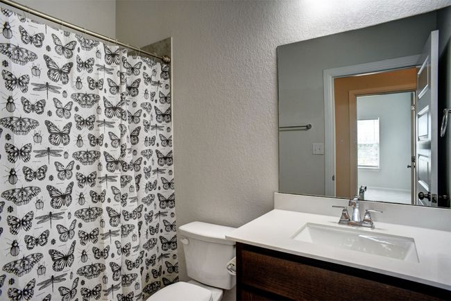 Full bath with toilet, a textured wall, vanity, and a shower with shower curtain | Image 29