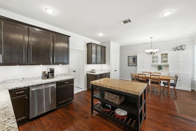 Kitchen with dishwasher, crown molding, a chandelier, dark brown cabinetry, and decorative light fixtures | Image 7