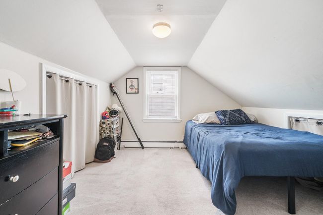 Bedroom featuring a baseboard heating unit, vaulted ceiling, and light colored carpet | Image 19
