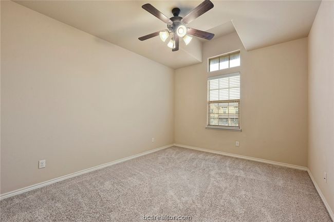 Carpeted spare room featuring lofted ceiling, a ceiling fan, and baseboards | Image 14