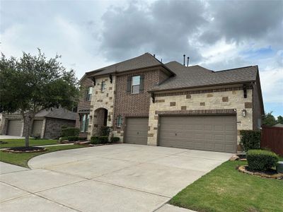 This is a two-story brick home with a spacious three-car garage and well-maintained landscaping. The exterior features a mix of brick and stone, giving it a sturdy and classic appearance. | Image 1