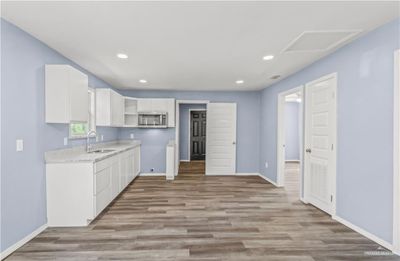 Kitchen featuring light stone counters, sink, white cabinetry, and light hardwood / wood-style floors | Image 3