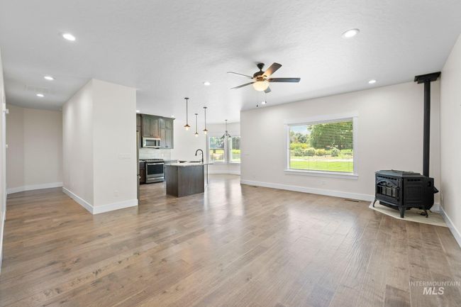 Unfurnished living room featuring a ceiling fan, light wood-type flooring, recessed lighting, and a wood stove | Image 13