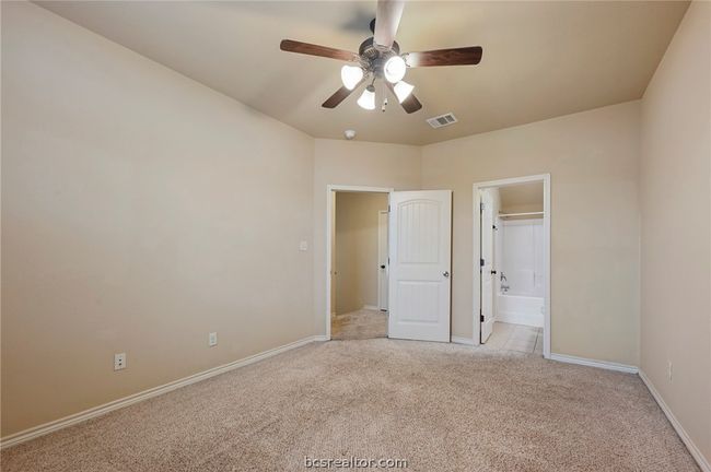 Unfurnished bedroom featuring visible vents, connected bathroom, baseboards, light colored carpet, and ceiling fan | Image 15