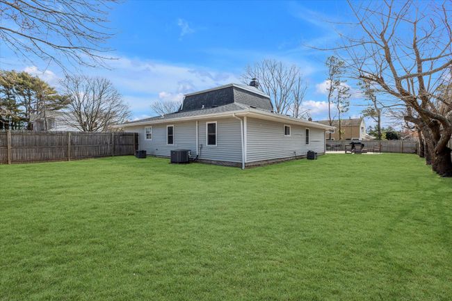 Back of property featuring a fenced backyard, a lawn, central AC, and roof with shingles | Image 18