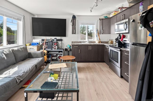 Kitchen featuring stainless steel appliances, track lighting, open floor plan, dark brown cabinetry, and light wood finished floors | Image 43