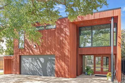 The redwood siding and the walls of windows and black poles continue throughout the home for its unique architectural design. | Image 1