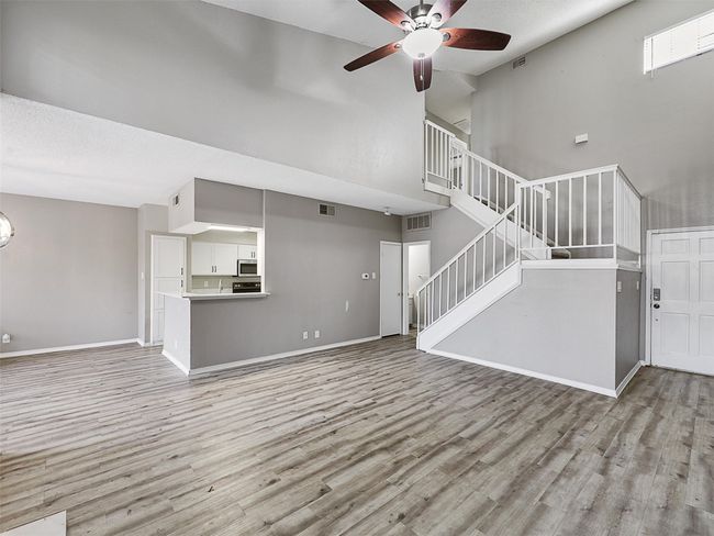 Unfurnished living room with visible vents, stairway, ceiling fan, and wood finished floors | Image 5