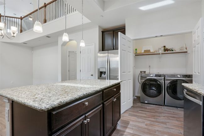 Laundry area featuring separate washer and dryer, light wood-type flooring, arched walkways, a towering ceiling, and laundry area | Image 9