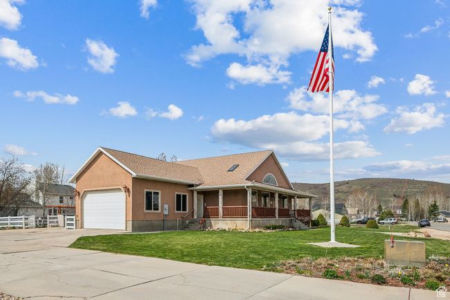 View of front of home featuring concrete driveway, covered porch, fence, a front yard, and a garage | Image 57