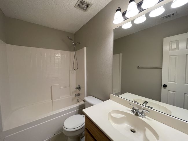 Full bath featuring a textured ceiling, shower / bathtub combination, and vanity | Image 10