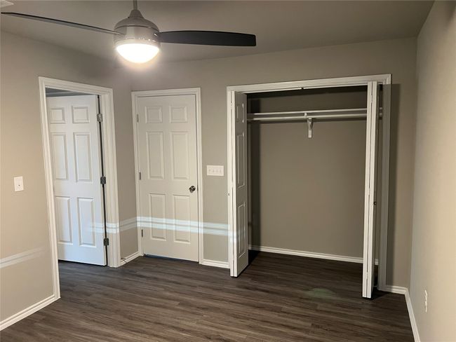 Unfurnished bedroom with dark wood finished floors, baseboards, a closet, and a ceiling fan | Image 13