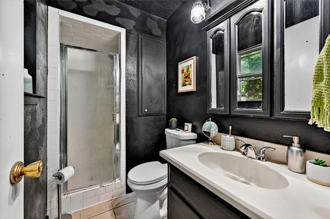 Full bathroom featuring a shower stall, vanity, tile patterned floors, and a textured wall | Image 19