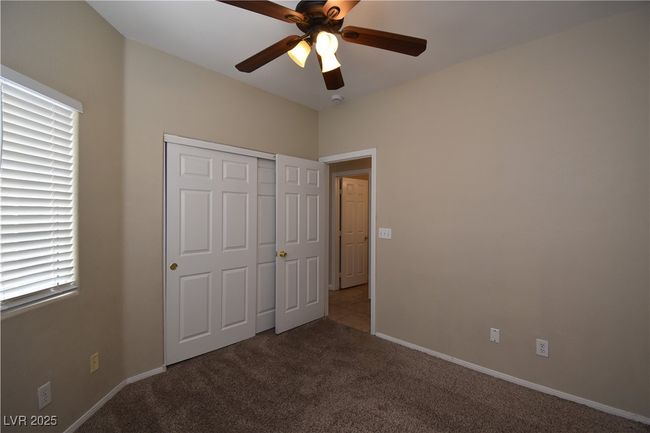 Unfurnished bedroom featuring a ceiling fan, baseboards, carpet floors, and a closet | Image 11