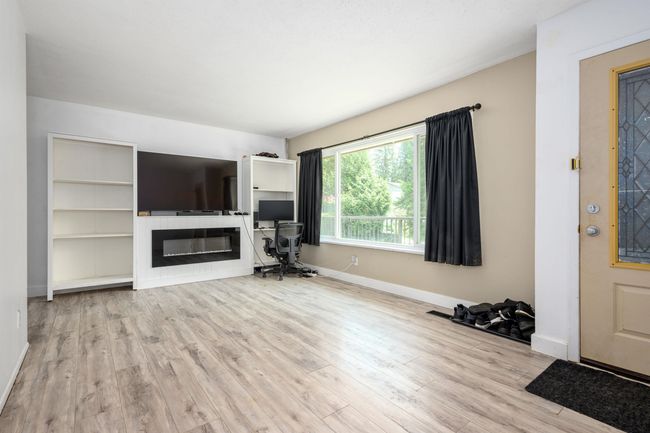 Unfurnished living room with a glass covered fireplace, wood finished floors, and baseboards | Image 11