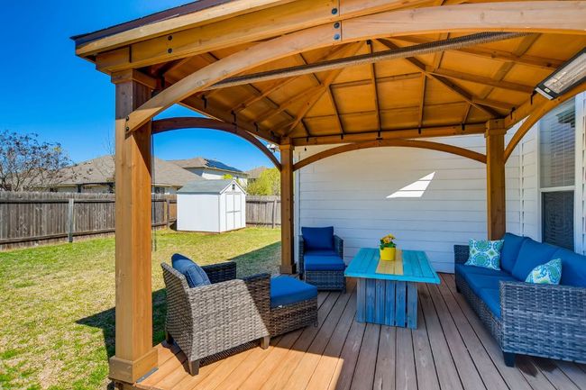 Wooden deck with a gazebo, outdoor lounge area, a fenced backyard, and a storage shed | Image 24