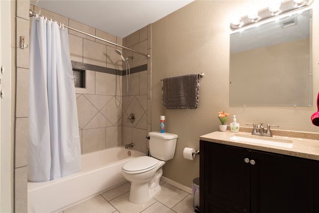 Bathroom featuring tile patterned flooring, vanity, shower / bathtub combination with curtain, toilet, and baseboards | Image 13