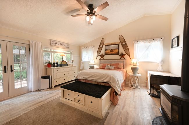 Bedroom with access to exterior, vaulted ceiling, light wood-type flooring, a wood stove, and french doors | Image 29