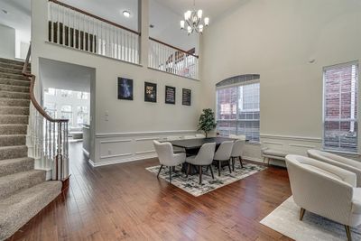 Dining space with a towering ceiling, dark wood-type flooring, and a chandelier | Image 3