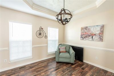 Living area featuring dark hardwood / wood-style flooring, a raised ceiling, and a notable chandelier | Image 3