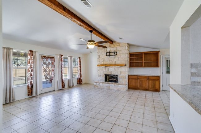 Unfurnished living room featuring visible vents, a ceiling fan, a fireplace, light tile patterned floors, and a healthy amount of sunlight | Image 6