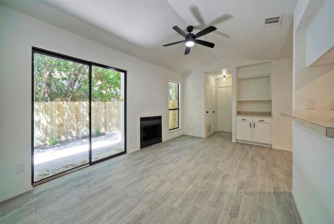Unfurnished living room with ceiling fan, light wood finished floors, a fireplace, plenty of natural light, and vaulted ceiling | Image 6