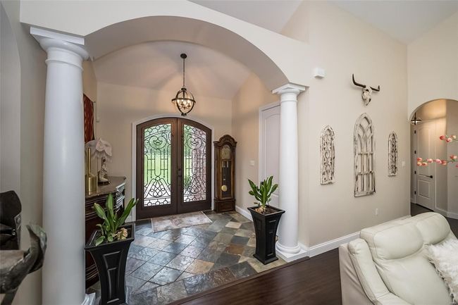 Foyer with arched walkways, french doors, stone tile floors, baseboards, and decorative columns | Image 7