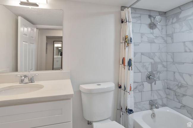 Bathroom with shower / bath combination with curtain, toilet, and vanity | Image 13