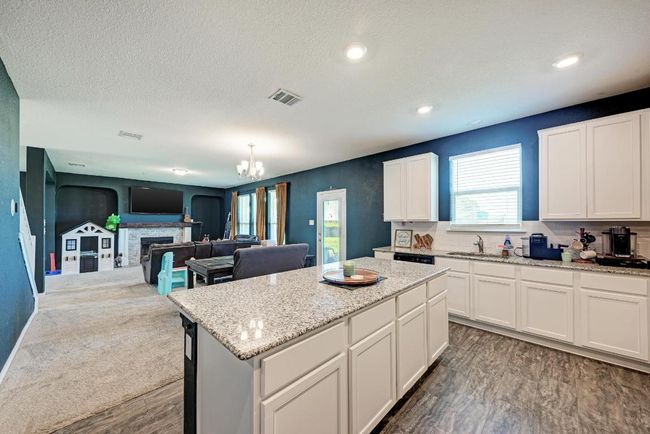 Kitchen with dark wood-style floors, a chandelier, a kitchen island, white cabinetry, and a textured ceiling | Image 18