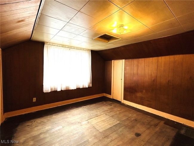 Additional living space with lofted ceiling, hardwood / wood-style flooring, wooden walls, and baseboards | Image 10