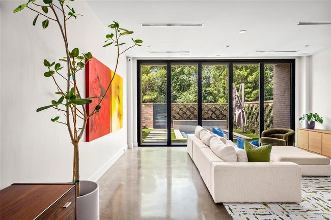 Walls of floor-to-ceiling Ram windows frame uninterrupted tree-line views and flood the living space with natural light, blurring the line between indoors and out. With Memorial Park just beyond the gate, this open-concept layout offers an effortless connection to nature, while polished concrete floors and modern finishes ground the serene, contemporary aesthetic. | Image 7