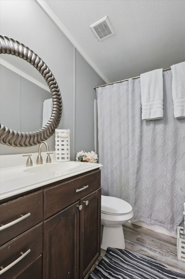 Full bath featuring wood finished floors, vanity, curtained shower, toilet, and visible vents | Image 20