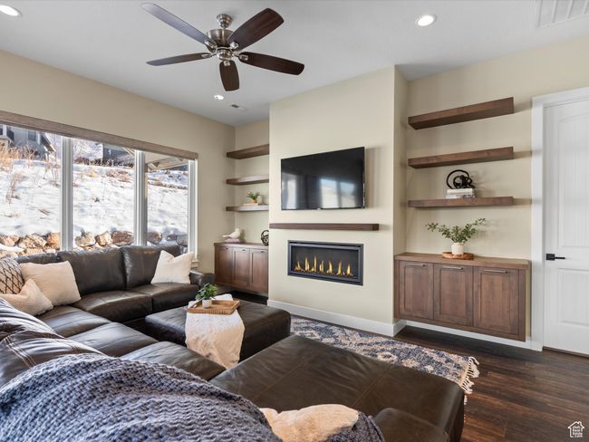 Living area with a glass covered fireplace, a ceiling fan, recessed lighting, dark wood-style flooring, and baseboards | Image 4
