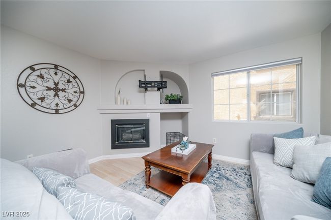 Living room with a glass covered fireplace, wood finished floors, and baseboards | Image 4