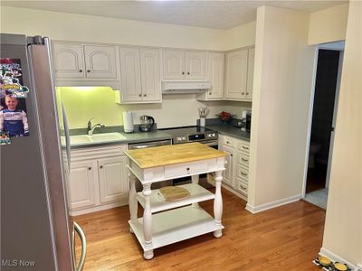 Kitchen featuring appliances with stainless steel finishes, white cabinetry, wood counters, and light hardwood / wood-style floors | Image 3