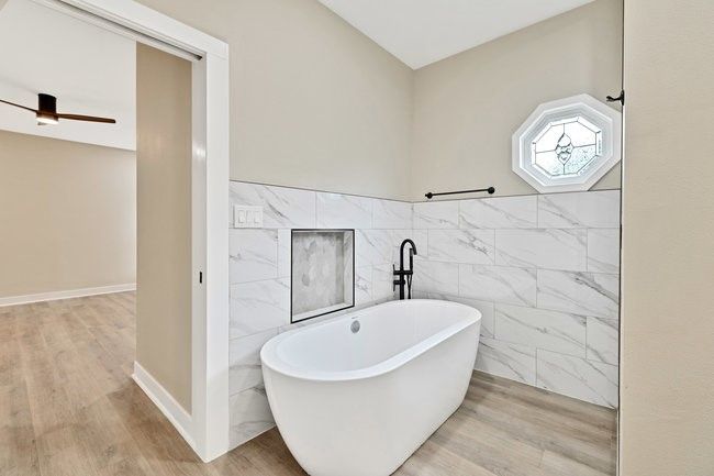 Bathroom with wood finished floors, a ceiling fan, a freestanding bath, and tile walls | Image 16