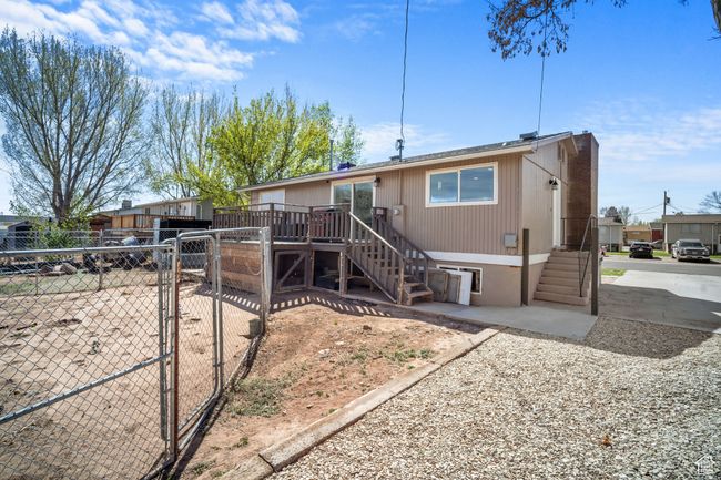View of front of property featuring a gate, stairs, a chimney, a deck, and fence | Image 24
