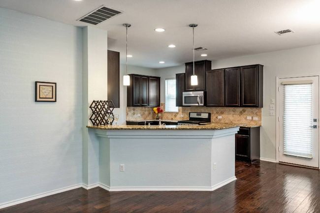 Kitchen with appliances with stainless steel finishes, tasteful backsplash, light stone countertops, dark brown cabinetry, and recessed lighting | Image 21