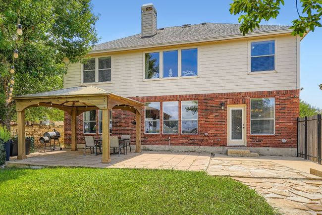 Back of house featuring a gazebo, a chimney, brick siding, a patio, and a shingled roof | Image 35