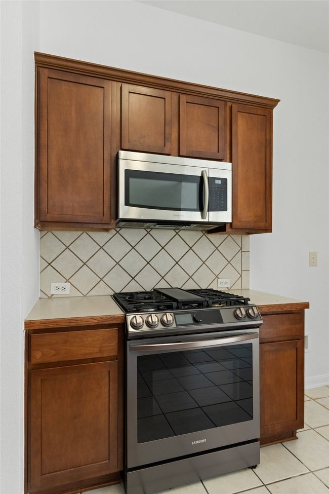 Kitchen featuring appliances with stainless steel finishes, tasteful backsplash, light countertops, and light tile patterned floors | Image 14