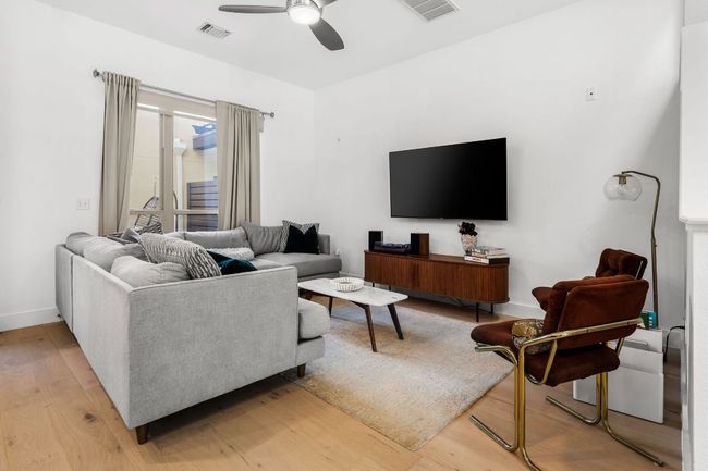 Living area with baseboards, a ceiling fan, visible vents, and light wood-style flooring | Image 13