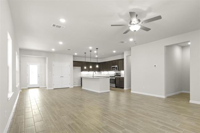 Unfurnished living room with light wood-style floors, ceiling fan, visible vents, and recessed lighting | Image 7