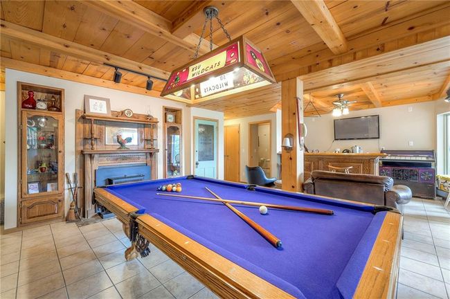 Game room featuring a wooden ceiling with exposed beams, a fireplace, tile patterned floors, pool table, and rail lighting | Image 39