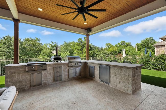 View of patio featuring an outdoor kitchen, ceiling fan, and view of scattered trees | Image 30