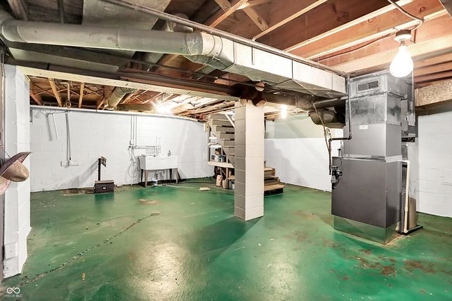 unfinished below grade area featuring heating unit, a sink, and stairway | Image 37