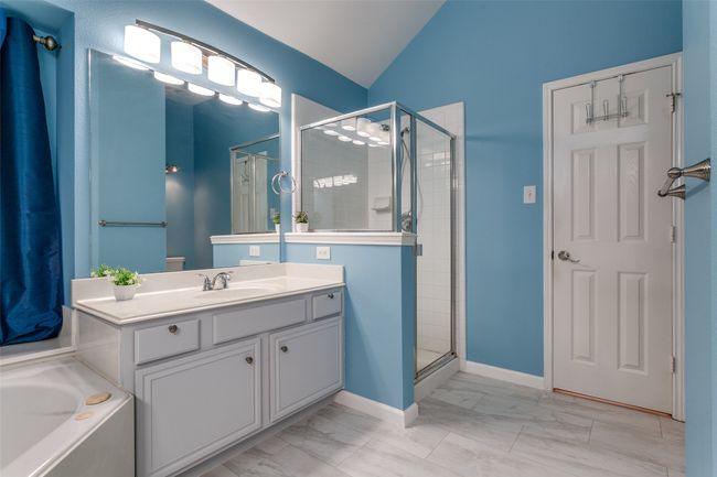 Bathroom featuring marble finish floors, a stall shower, vanity, lofted ceiling, and a garden tub | Image 16