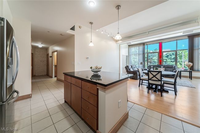 Kitchen featuring dark countertops, light tile patterned flooring, stainless steel fridge with ice dispenser, a center island, and open floor plan | Image 13