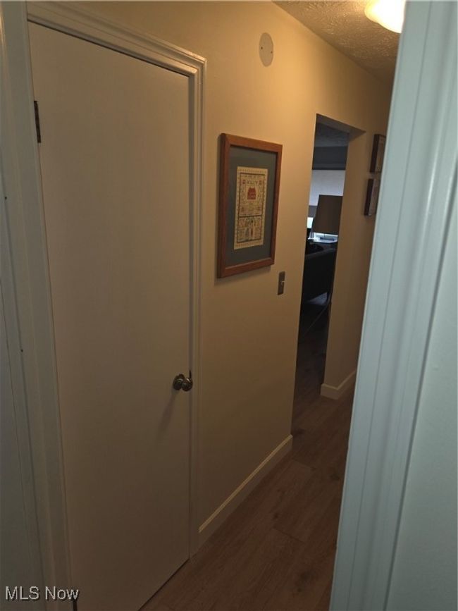 Hall featuring dark wood-type flooring, baseboards, and a textured ceiling | Image 22
