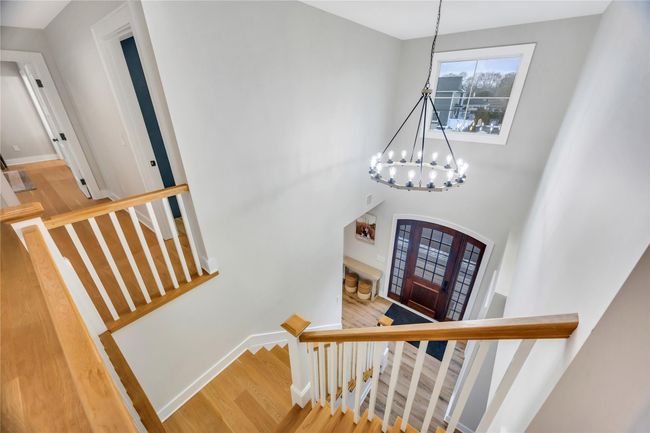 Staircase featuring an inviting chandelier, baseboards, a high ceiling, arched walkways, and wood finished floors | Image 29